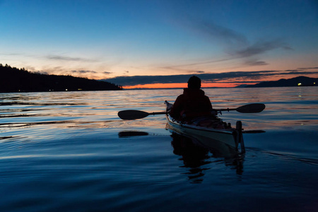 在充满活力的日落中，人们在海上皮划艇上皮划艇。 取近杰里科海滩温哥华不列颠哥伦比亚省加拿大。