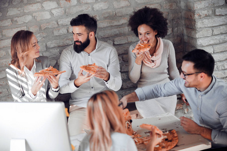 快乐的年轻商业团队在办公室吃披萨。商业食品和人的概念。