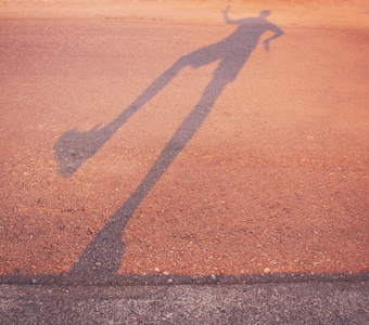 在日出或日落时, 一个人沿着路边跳舞的长阴影与复古复古 instagram 过滤器