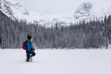 冒险妇女正在美丽的加拿大雪覆盖景观雪鞋在冬季。 摄于加拿大不列颠哥伦比亚省温哥华以北的乔弗尔湖。