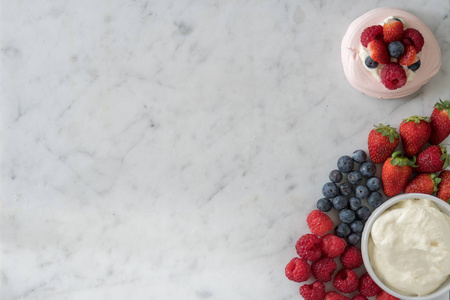 meringue旁边是精选的覆盆子草莓蓝莓和奶油，上面是大理石桌面，有复制空间