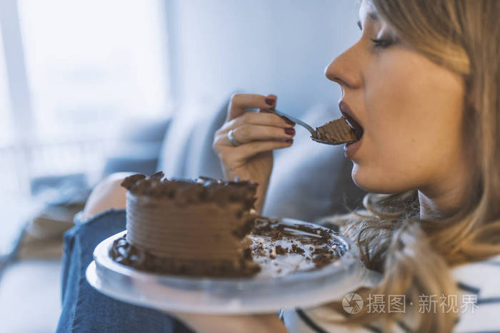 漂亮的女孩喜欢吃巧克力蛋糕.漂亮的年轻女人吃一个甜蛋糕.