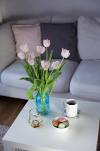 内部.一束郁金香在玻璃花瓶, 热茶, 蜡烛站在咖啡桌上。房间.舒适.沙发