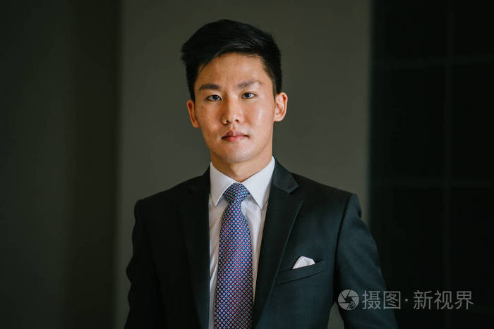 亚洲男人的肖像,穿着一套专业的深色西装,白色衬衫,背景很黑.