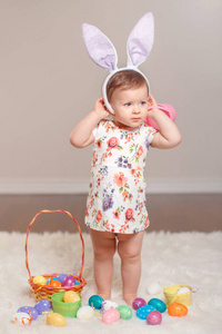 可爱的白种人女婴穿着复活节兔子耳朵在室内演播室里玩。 小孩拿着篮子，鸡蛋庆祝传统的基督教节日