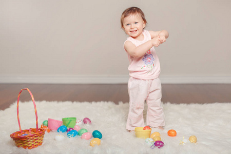 可爱可爱的白种人女婴穿着粉红色衬衫和裤子庆祝传统复活节基督教节日。 小孩拿着篮子玩彩蛋