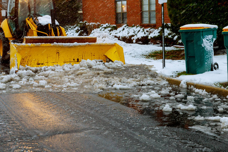 拖拉机装载机清扫积雪后，一辆降雪车清除道路上的积雪