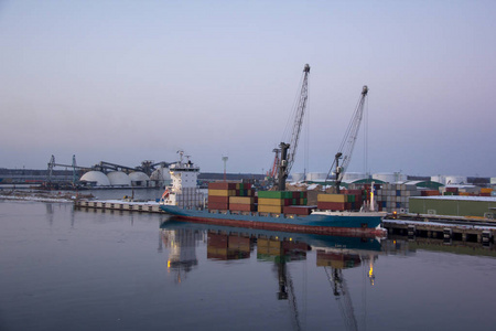 码头的货运集装箱和天然气油罐。在进出口和商业物流方面。货船停靠在港口.拉托维亚里加港的货运起重机。
