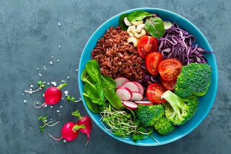佛陀碗餐与甘蓝菠菜和猪油叶糙米，番茄西兰花，萝卜，新鲜绿芽和松子。 健康平衡的营养。 素食。 间接视图