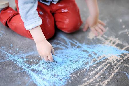 在沥青上用彩色粉笔绘制的小小孩男孩的特写照片