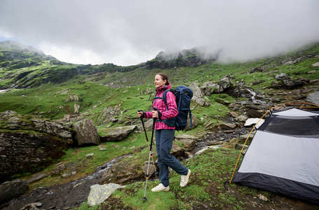 快乐的年轻女子微笑着环顾四周站在她的帐篷在山边徒步旅行 copyspace 背包徒步旅行设备生活方式活动爱好休闲旅行自然