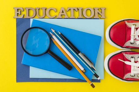 教育的概念。红色运动鞋, 学校用品, 书, 黄色背景的笔记本电脑