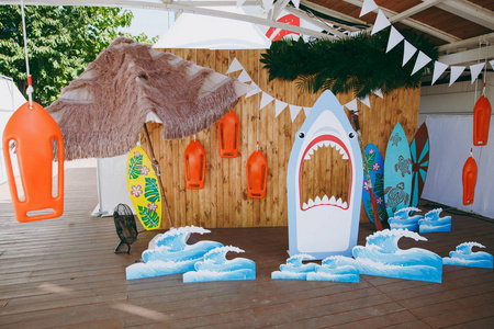 美丽的风景和设计的一个孩子的生日聚会的海洋风格与冲浪者, 鲨鱼, 波浪, 花环在露天遮阳篷下。家庭假期的组织与装饰