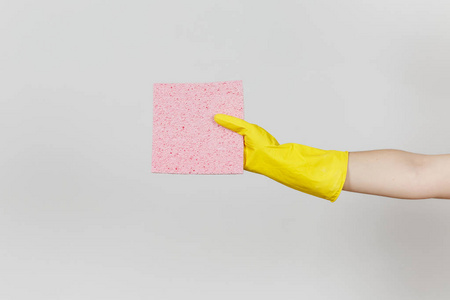 女性手在黄色手套的关闭水平持有粉红色的吸水餐巾清洁和洗涤的菜肴在白色背景下隔离。清洁用品的概念。复制广告空间