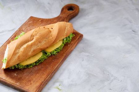 新鲜和美味的三明治与奶酪和蔬菜在切割板上的白色纹理背景, 选择性聚焦