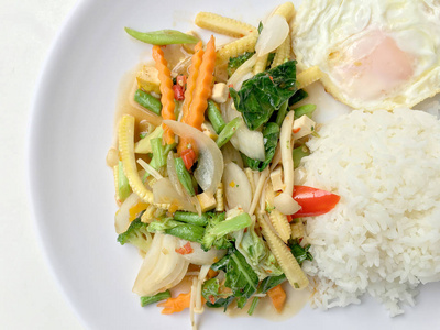 将蔬菜与肉汁酱和泰国式炒鸡蛋混合在白色背景的白色盘子中。素食，健康食品..