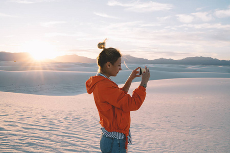 年轻的女性旅行者拍摄美丽的沙丘景观，在度假期间探索著名的地标