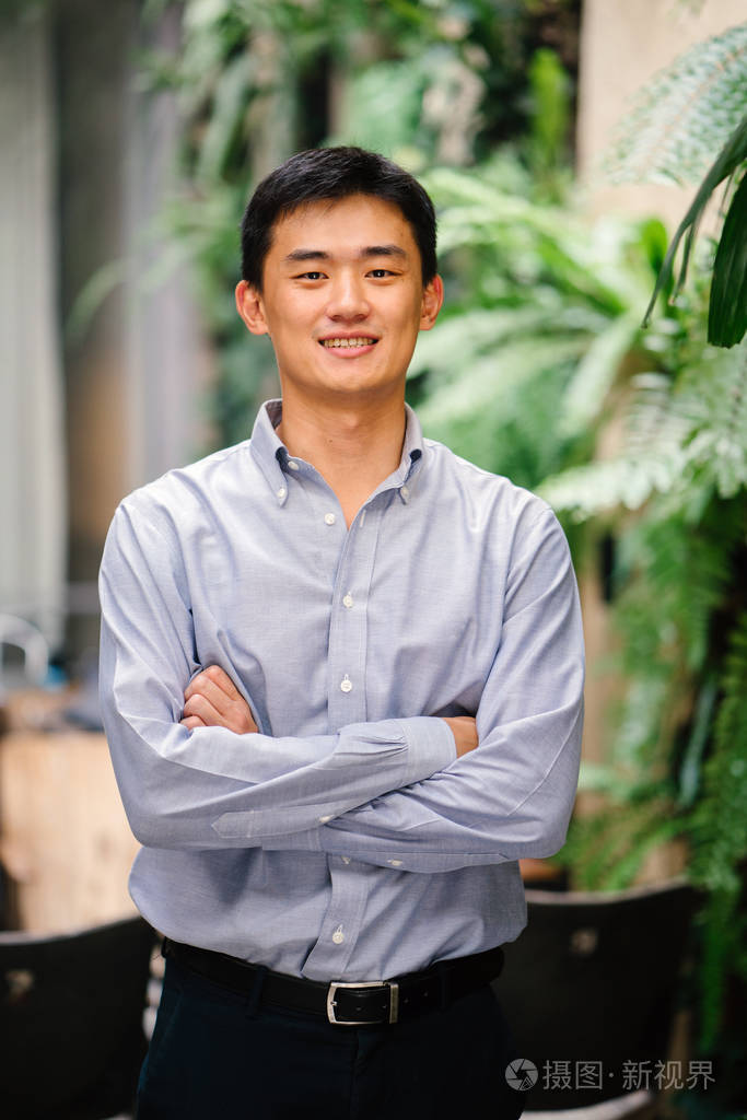 一位英俊,年轻,聪明的中国亚洲男人穿着西装,微笑着站