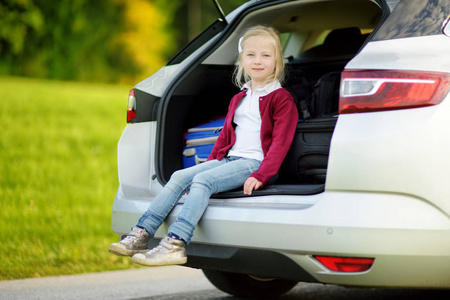 可爱的女孩带着手提箱准备和她的父母一起度假。 期待道路旅行或旅行的孩子。 学校的秋假。 和孩子们一起坐车旅行。