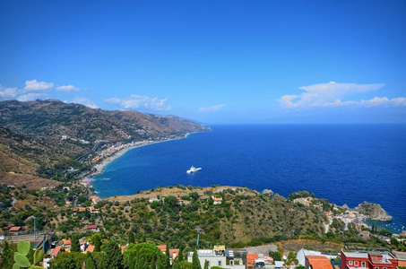 意大利托米纳西西里2015年8月26日，从希腊剧院到大海的壮丽全景。 郁郁葱葱的自然地中海植被花卉。 海和船。
