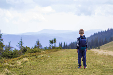 小男孩带着背包徒步旅行, 在风景秀丽的夏日绿山山上。儿童独享山水山景。积极的生活方式, 冒险和周末活动的概念
