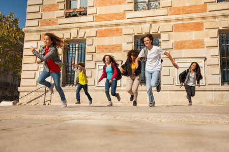 快乐的十几岁的男孩和女孩下课后从大学大楼里跑出来