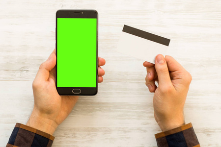 色度键合成在线支付塑料卡智能手机与绿色屏幕手拿黑色智能手机与绿色屏幕