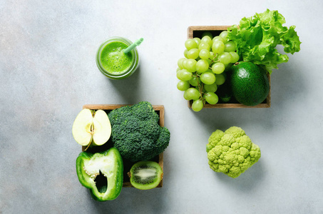 绿色冰沙在玻璃罐子与新鲜的有机绿色蔬菜和果子在灰色背景。春季饮食, 健康生素食, 素食观念, 排毒早餐, 碱性洁食。复制空间