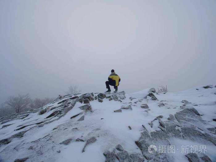 照片 高大的徒步旅行者在黑色的世界巅峰.山谷中的厚橙色薄雾波纹管.