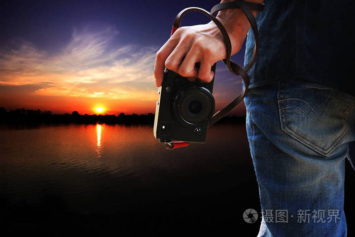 男人手里拿着相机在夕阳下大自然的背景下照片-正版7