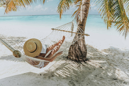 旅行系列。马尔代夫群岛。女孩在吊床上放松，看书