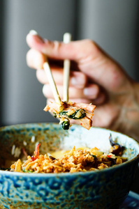 手持筷子的人手上放着一盘日式泰语中餐饭蘑菇蔬菜。咖啡厅, 餐厅。商务午餐。复制空间