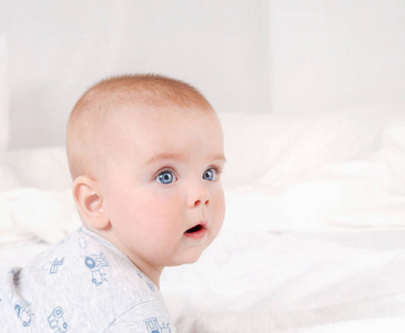 可爱新生儿的特写肖像。幸福的微笑孩子，蓝眼睛，白色的床底
