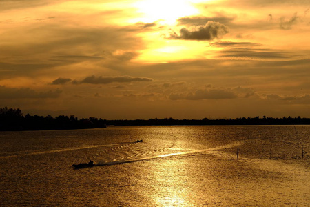 日落在湖和天空与金色的云。 美丽的水反射。 在湖上日落之后