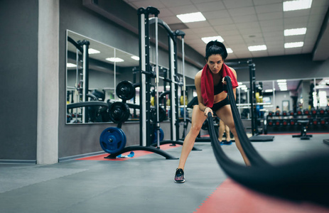 体育锻炼年轻适合女性在功能训练健身房做 crossfit 运动用战斗绳索, copyspace 为您的文本。交叉配合锻炼的动机。