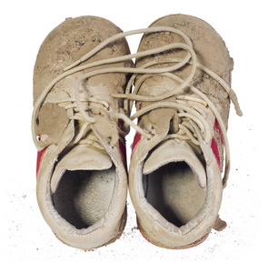 儿童的小鞋子布满了泥巴。儿童肮脏紧身裤