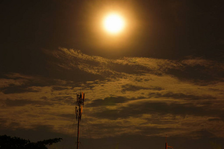 在美丽的夜晚和通信技术网络的塔上，满月带云