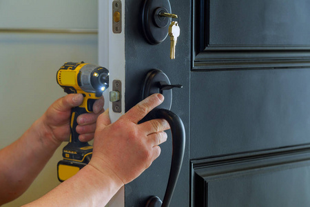 一个专业的锁匠安装一个新的锁在房子的外部门与锁的内部部分的特写