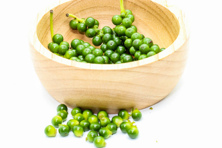 把新鲜的绿色胡椒贴在木制杯子上，白色背景