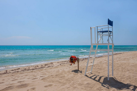 海洋救生员的椅子，靠在阳光和雨伞的背面。 背景蓝天白云在阳光明媚的夏日。 游客安全概念