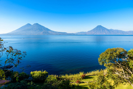 清晨，从阿蒂特兰湖观看蓝色的天空和清澈的水，美丽的魔法湖，危地马拉高地的火山和土著人民的照片拍摄在帕纳贾切尔附近，那里是最旅游的