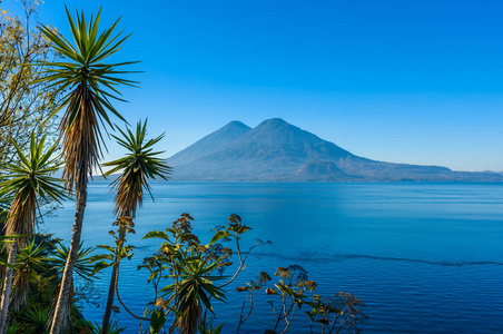 清晨，从阿蒂特兰湖观看蓝色的天空和清澈的水，美丽的魔法湖，危地马拉高地的火山和土著人民的照片拍摄在帕纳贾切尔附近，那里是最旅游的