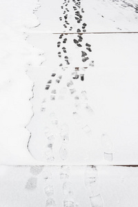 人行道上新雪中的脚印。 城里的冰雪。