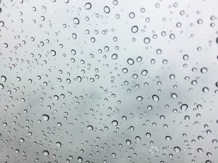 挡风玻璃或挡风玻璃或汽车玻璃上的雨滴. 从车内观看灰色天空背景.