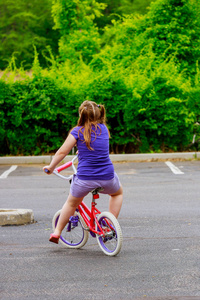 阳光明媚的一天，小女孩骑自行车。骑自行车的快乐孩子