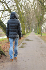 寒冷的雨天，孤独的女人在公园里散步