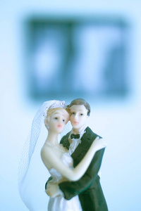 新婚夫妇结婚蛋糕顶部塑料人物与燕尾服晚礼服白色婚礼礼服面纱。
