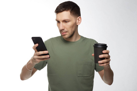 体贴认真的黑发男企业家在卡其色T恤有咖啡休息后，努力工作做商业报告，通过现代数字电话免费互联网连接等待来自合作伙伴的电话。