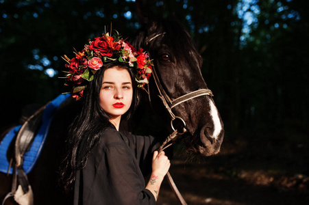 神秘的女孩戴着花环，穿着黑色的衣服，马穿着木头。