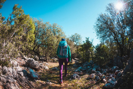 一个女人带着背包在火鸡周围旅行。 沿着山路走。 一个女孩在炎热的一天沿着石路走。 积极的生活方式。 游客检查风景如画的地方。